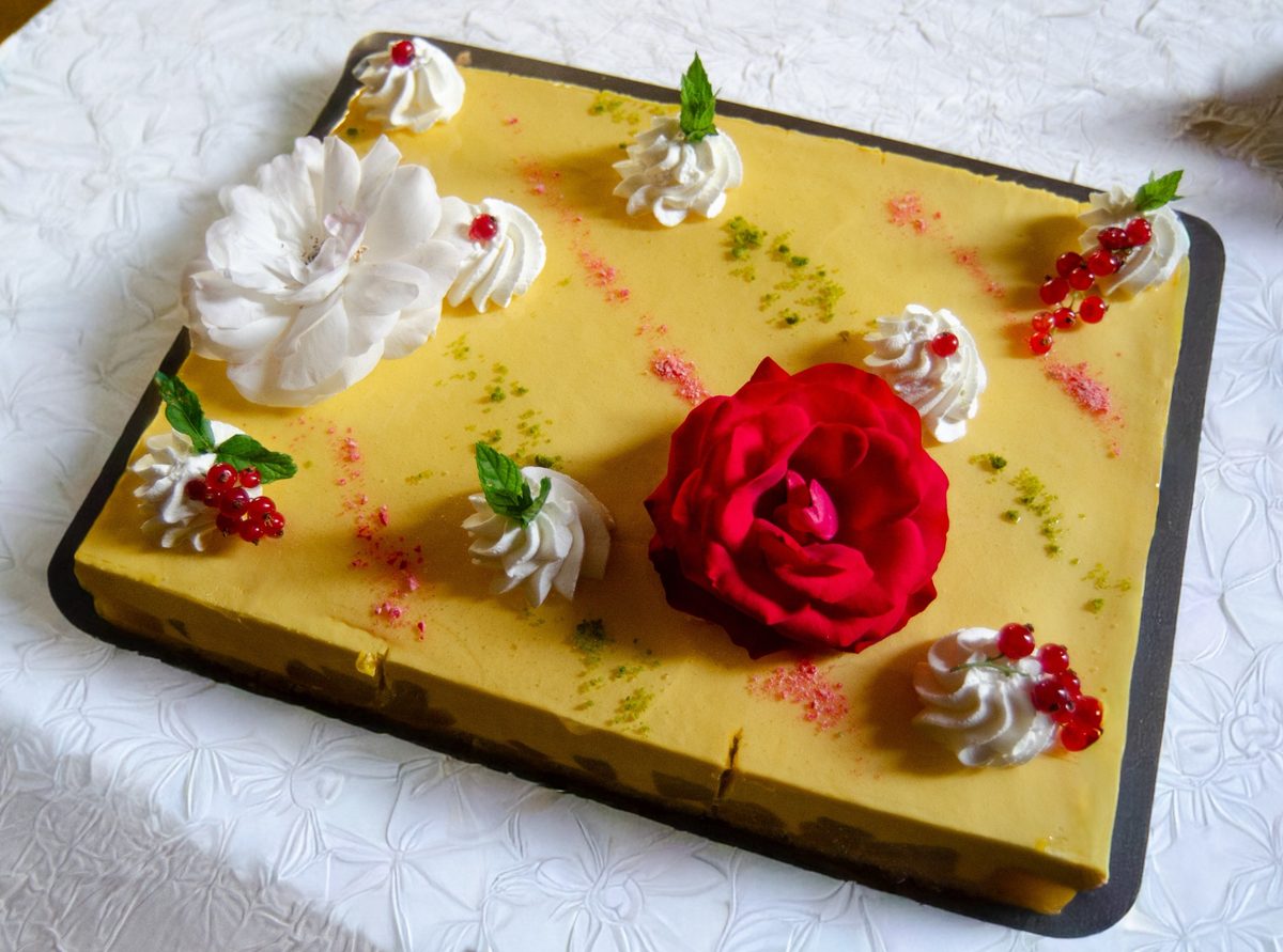 Gâteau mangue coco décoré de fleurs, de chantilly et de groseilles